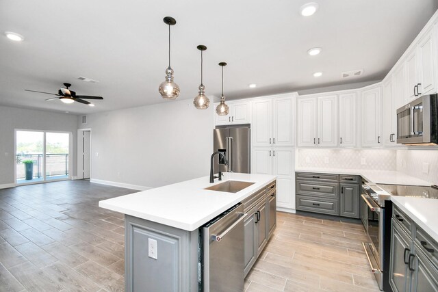 kitchen with stainless steel appliances, tasteful backsplash, gray cabinets, visible vents, and a sink