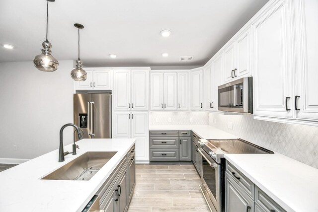 kitchen featuring premium appliances, gray cabinets, a sink, and tasteful backsplash