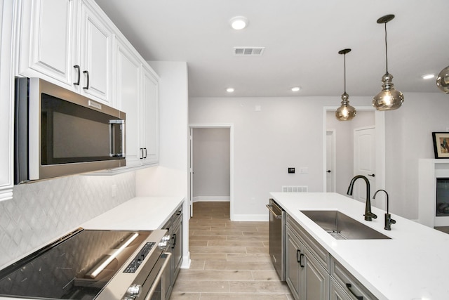 kitchen featuring wood finish floors, tasteful backsplash, visible vents, appliances with stainless steel finishes, and a sink