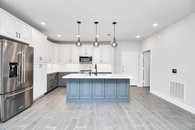 kitchen featuring light countertops, visible vents, appliances with stainless steel finishes, wood tiled floor, and a sink