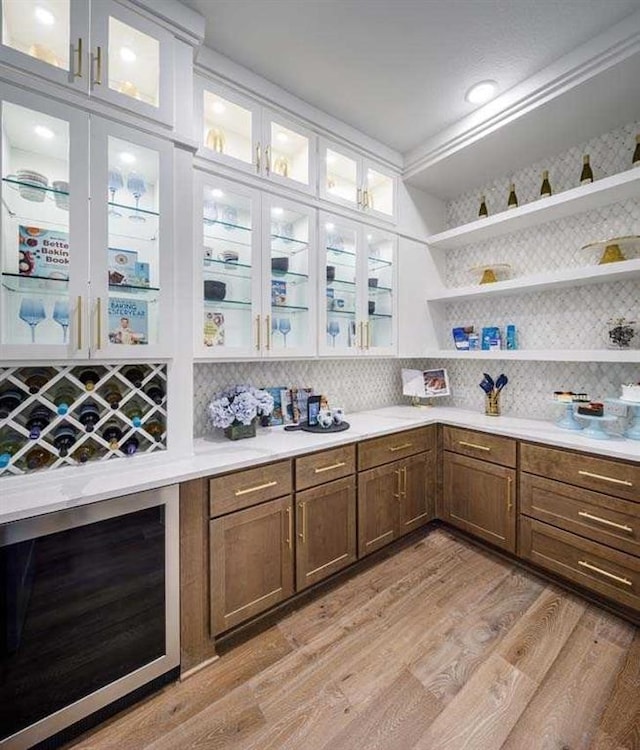 bar with light hardwood / wood-style floors, ornamental molding, tasteful backsplash, and wine cooler