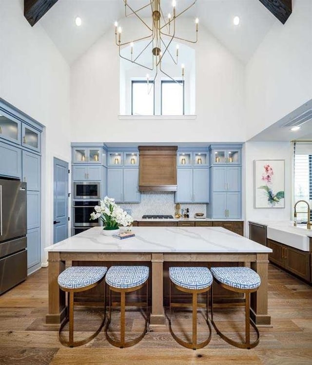 kitchen with appliances with stainless steel finishes, high vaulted ceiling, sink, and a spacious island