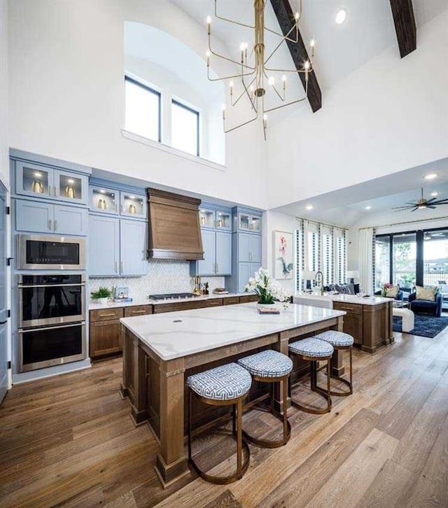 kitchen featuring pendant lighting, premium range hood, light stone countertops, and a spacious island