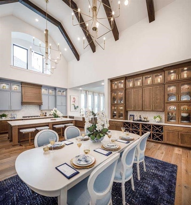 dining area featuring high vaulted ceiling, light wood-type flooring, beamed ceiling, and an inviting chandelier