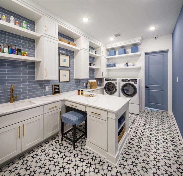 clothes washing area with independent washer and dryer, cabinets, and sink