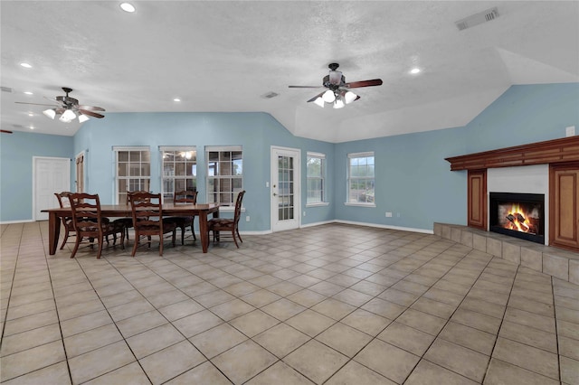 tiled living room featuring lofted ceiling, a tiled fireplace, a textured ceiling, and ceiling fan