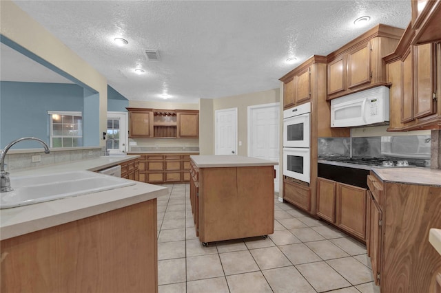 kitchen with a textured ceiling, sink, a center island, and white appliances