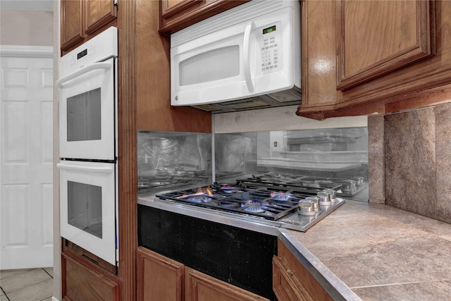 kitchen with tasteful backsplash, light tile patterned flooring, and white appliances