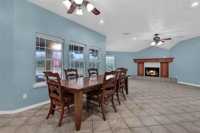 tiled dining room featuring ceiling fan, lofted ceiling, and a fireplace