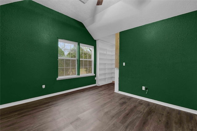 unfurnished room featuring lofted ceiling, ceiling fan, hardwood / wood-style floors, a textured ceiling, and built in shelves