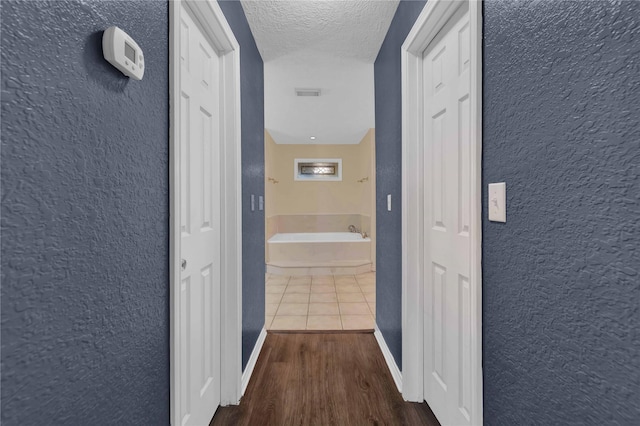 hall with a textured ceiling and hardwood / wood-style flooring