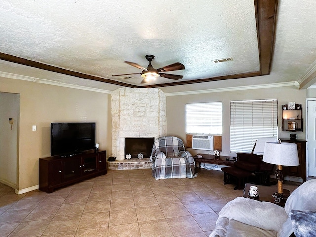 living room with a textured ceiling, light tile patterned floors, crown molding, ceiling fan, and a stone fireplace