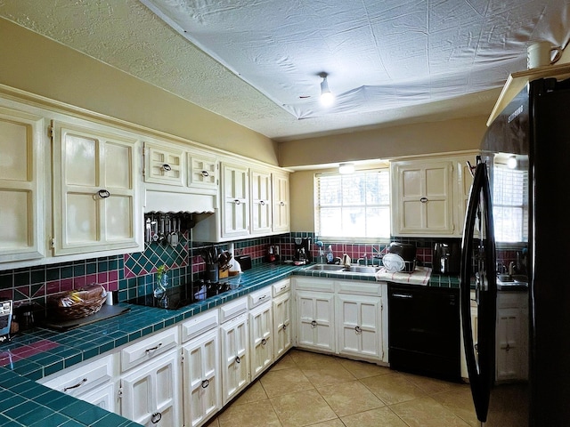 kitchen featuring dishwasher, tile countertops, light tile patterned floors, decorative backsplash, and sink