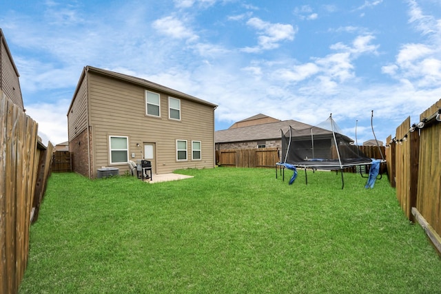 back of property with a patio, central AC unit, a lawn, and a trampoline