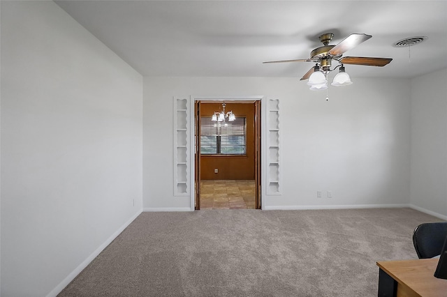 spare room featuring built in shelves, ceiling fan with notable chandelier, and carpet