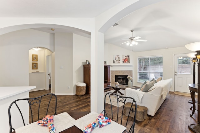 dining space with lofted ceiling, a tile fireplace, dark wood-type flooring, and ceiling fan