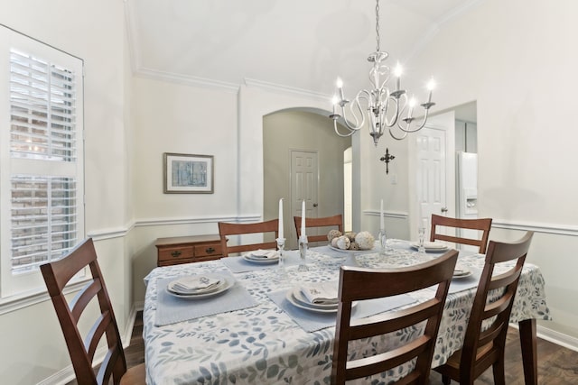 dining space with dark wood-type flooring, an inviting chandelier, and ornamental molding