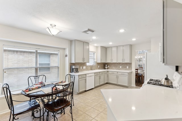 kitchen featuring range, backsplash, white dishwasher, light tile patterned flooring, and sink