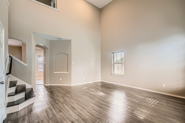 spare room featuring a towering ceiling and wood-type flooring