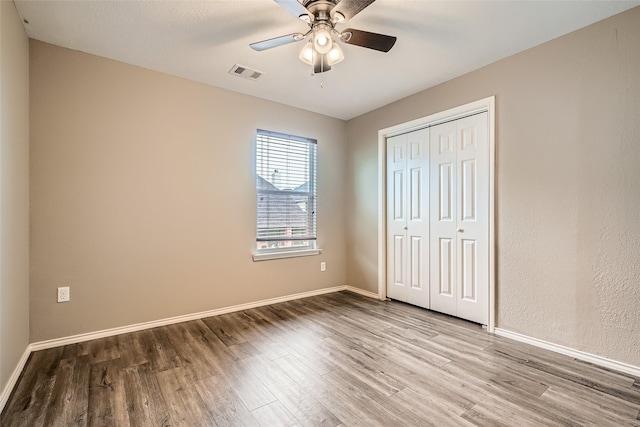 unfurnished bedroom featuring hardwood / wood-style flooring, ceiling fan, and a closet