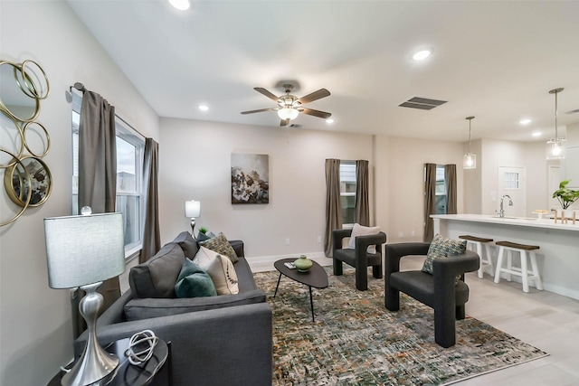 living room featuring ceiling fan, light hardwood / wood-style flooring, and sink