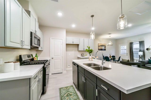 kitchen with sink, decorative light fixtures, white cabinets, a center island with sink, and appliances with stainless steel finishes