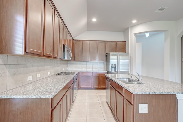 kitchen featuring sink, tasteful backsplash, light tile patterned floors, an island with sink, and appliances with stainless steel finishes