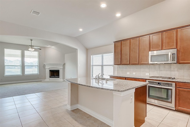 kitchen with a kitchen island with sink, stainless steel appliances, decorative backsplash, sink, and lofted ceiling