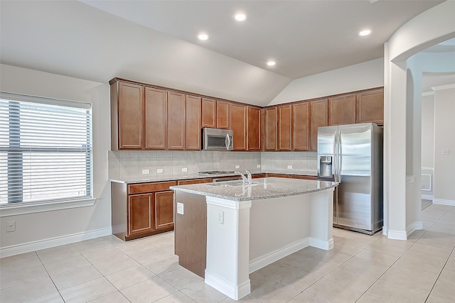 kitchen with sink, vaulted ceiling, tasteful backsplash, a kitchen island with sink, and appliances with stainless steel finishes