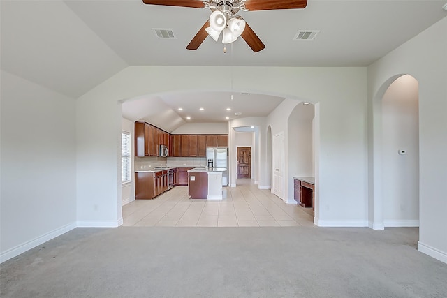 kitchen with vaulted ceiling, light colored carpet, stainless steel appliances, a center island, and ceiling fan