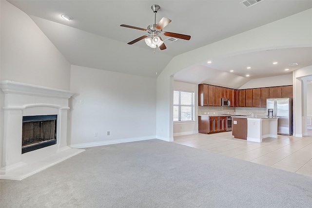 unfurnished living room featuring ceiling fan, vaulted ceiling, light carpet, and sink