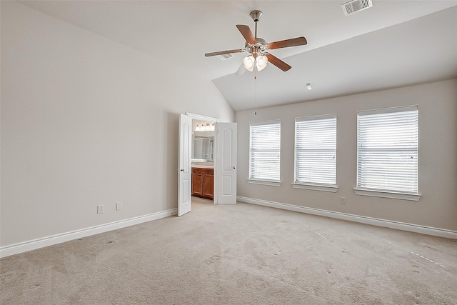 unfurnished bedroom featuring ceiling fan, light colored carpet, ensuite bathroom, and vaulted ceiling