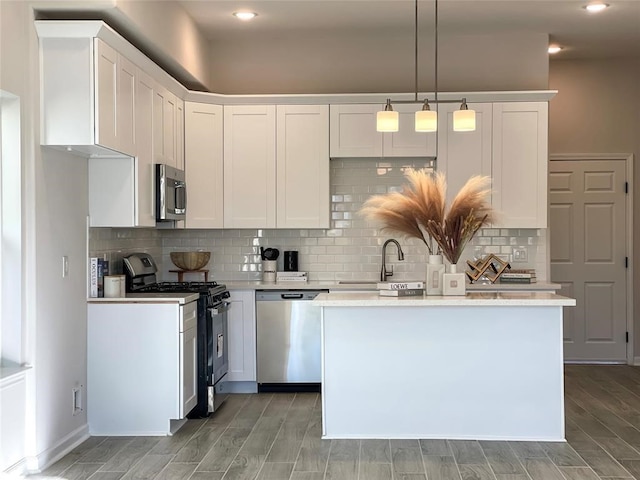 kitchen featuring stainless steel appliances, white cabinets, pendant lighting, and sink