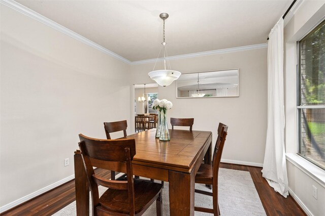 dining room with a notable chandelier, ornamental molding, and dark hardwood / wood-style flooring