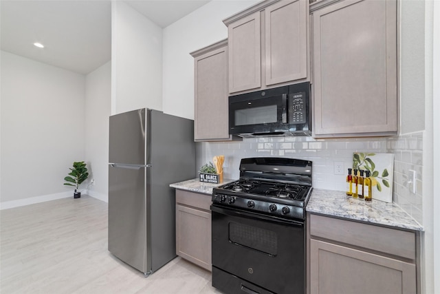 kitchen featuring backsplash, light stone countertops, and black appliances