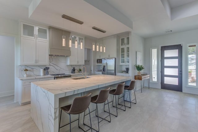 kitchen with decorative light fixtures, stainless steel appliances, a kitchen island with sink, a breakfast bar area, and sink