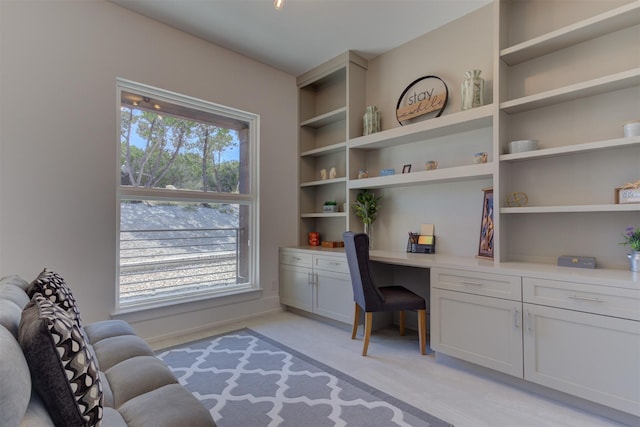 carpeted office with built in desk and a healthy amount of sunlight