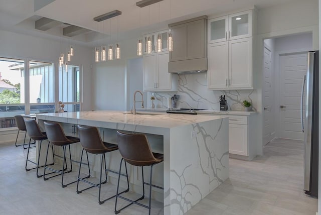 kitchen featuring sink, stainless steel fridge, an island with sink, and pendant lighting