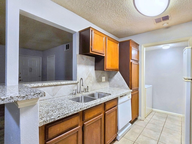 kitchen featuring sink, light tile patterned floors, dishwasher, and light stone countertops