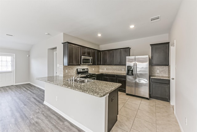 kitchen with kitchen peninsula, stainless steel appliances, sink, and decorative backsplash