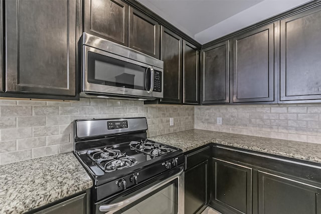 kitchen with range with gas stovetop, decorative backsplash, light stone counters, and dark brown cabinets