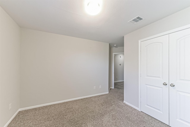 unfurnished bedroom featuring a closet and light colored carpet