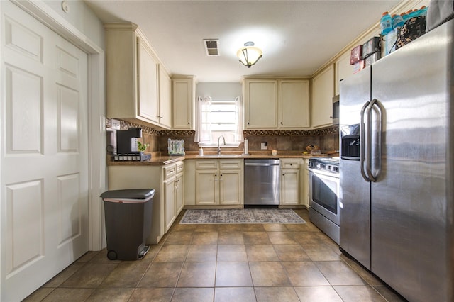 kitchen featuring stainless steel appliances, sink, tasteful backsplash, and cream cabinets