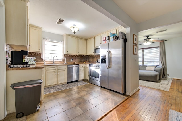 kitchen featuring sink, backsplash, cream cabinets, and appliances with stainless steel finishes