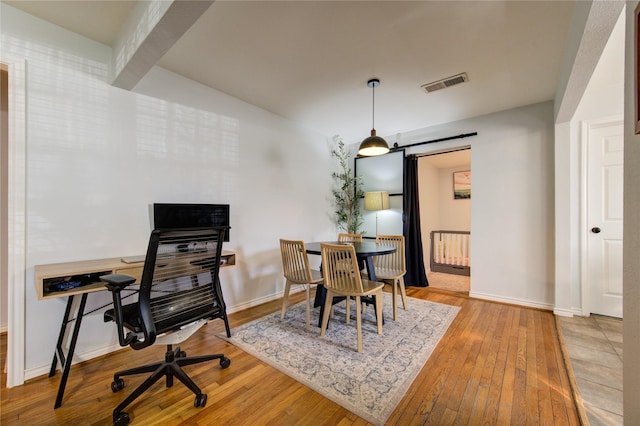 dining space with beamed ceiling and hardwood / wood-style floors