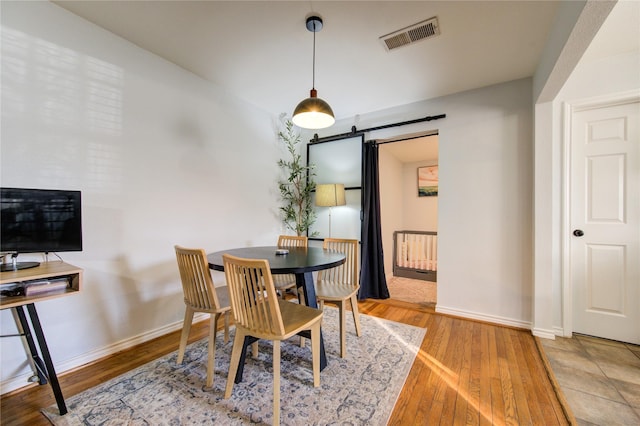 dining area featuring hardwood / wood-style flooring and a barn door