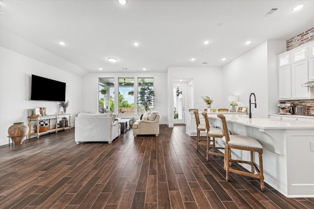 living room featuring vaulted ceiling and sink