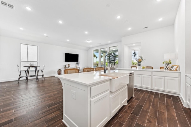 kitchen with sink, white cabinetry, a kitchen bar, an island with sink, and stainless steel dishwasher