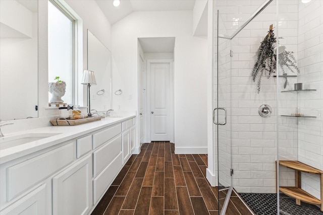 bathroom featuring a shower with door, vanity, vaulted ceiling, and a healthy amount of sunlight