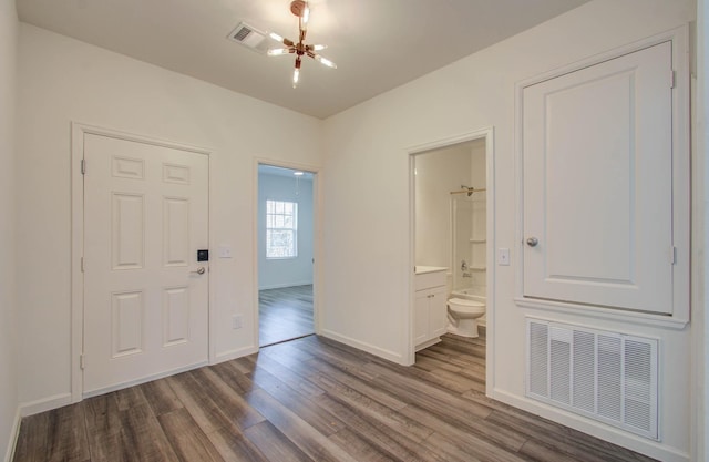 interior space with ensuite bath, a chandelier, and wood-type flooring